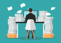 GettyImages-1177158970 man-writing-at-a-desk-surround-by-paper